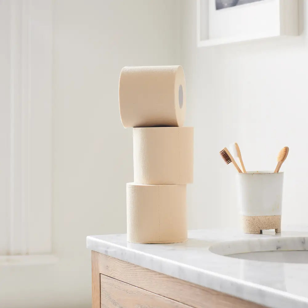 Unwhitened 100% bamboo toilet paper stacked up on bathroom surface