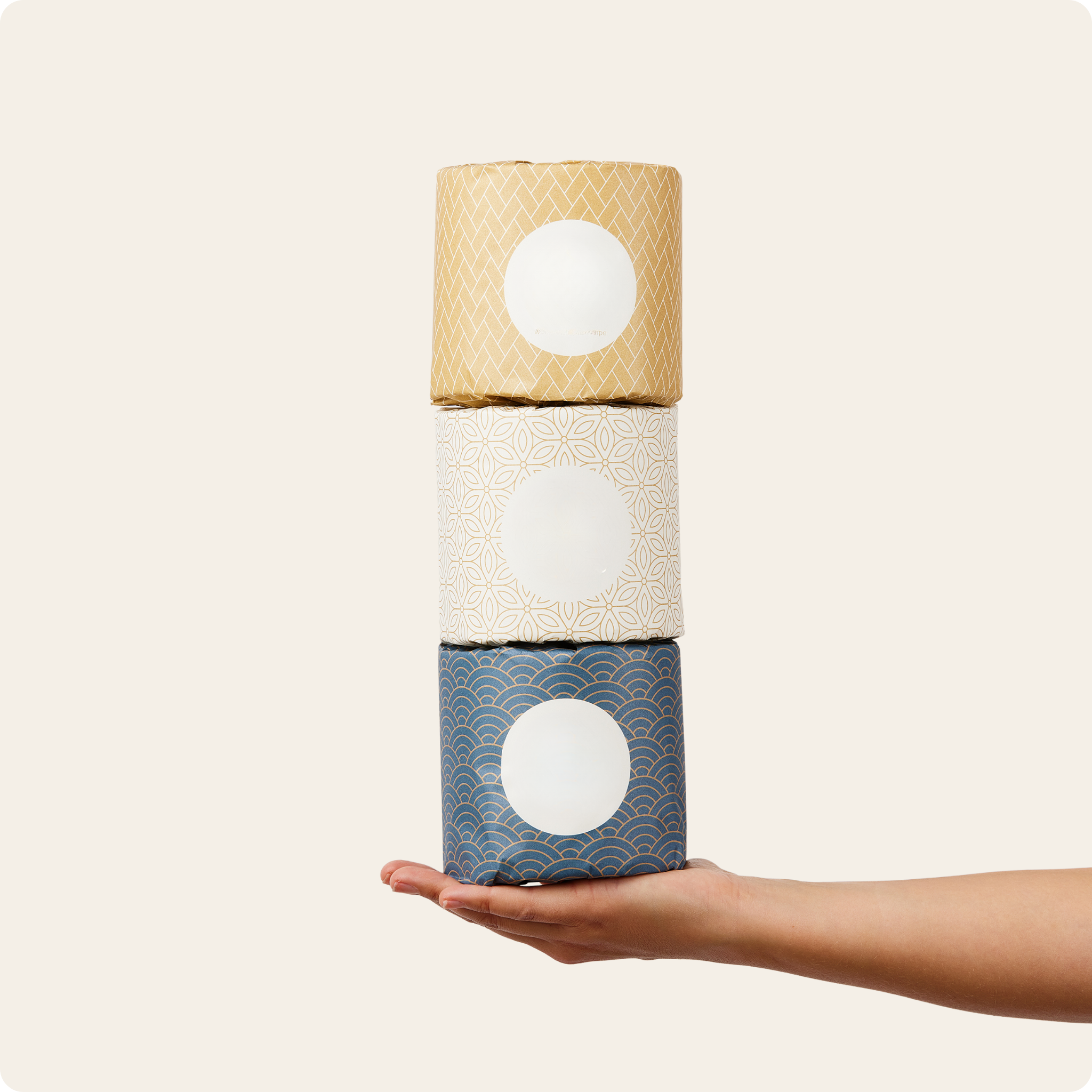 Three rolls of toilet paper stacked on a hand against a white background