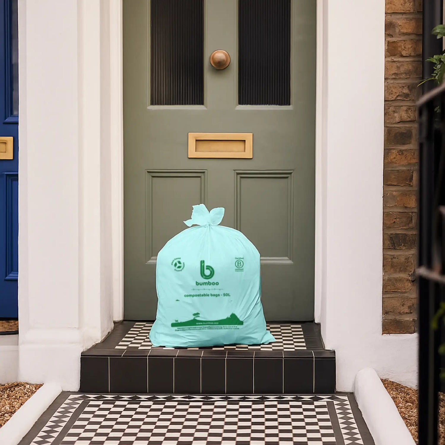 Green biodegradable bag on a doorstep in front of a green door.