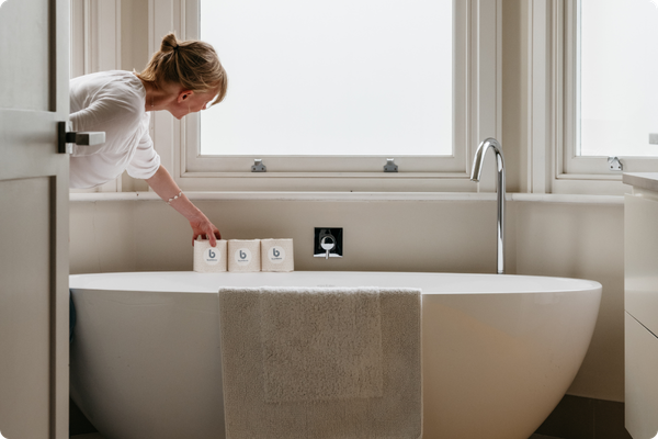 Woman in a bathroom with a freestanding bathtub and window