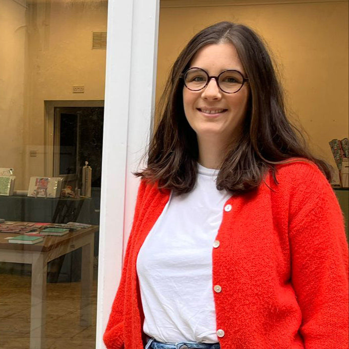 Woman wearing a red cardigan over a white shirt in an indoor setting