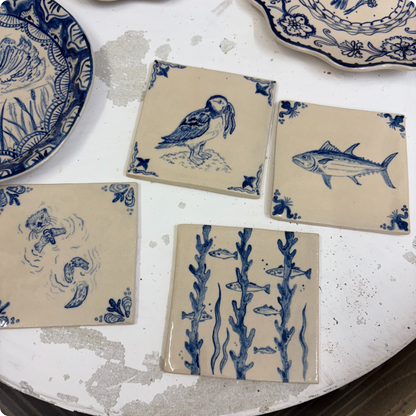Set of ceramic tiles with blue animal illustrations on a textured surface