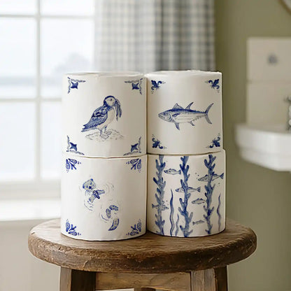 Four stacked toilet rolls with english deflt style wrappers featuring puffin, otter and tuna.