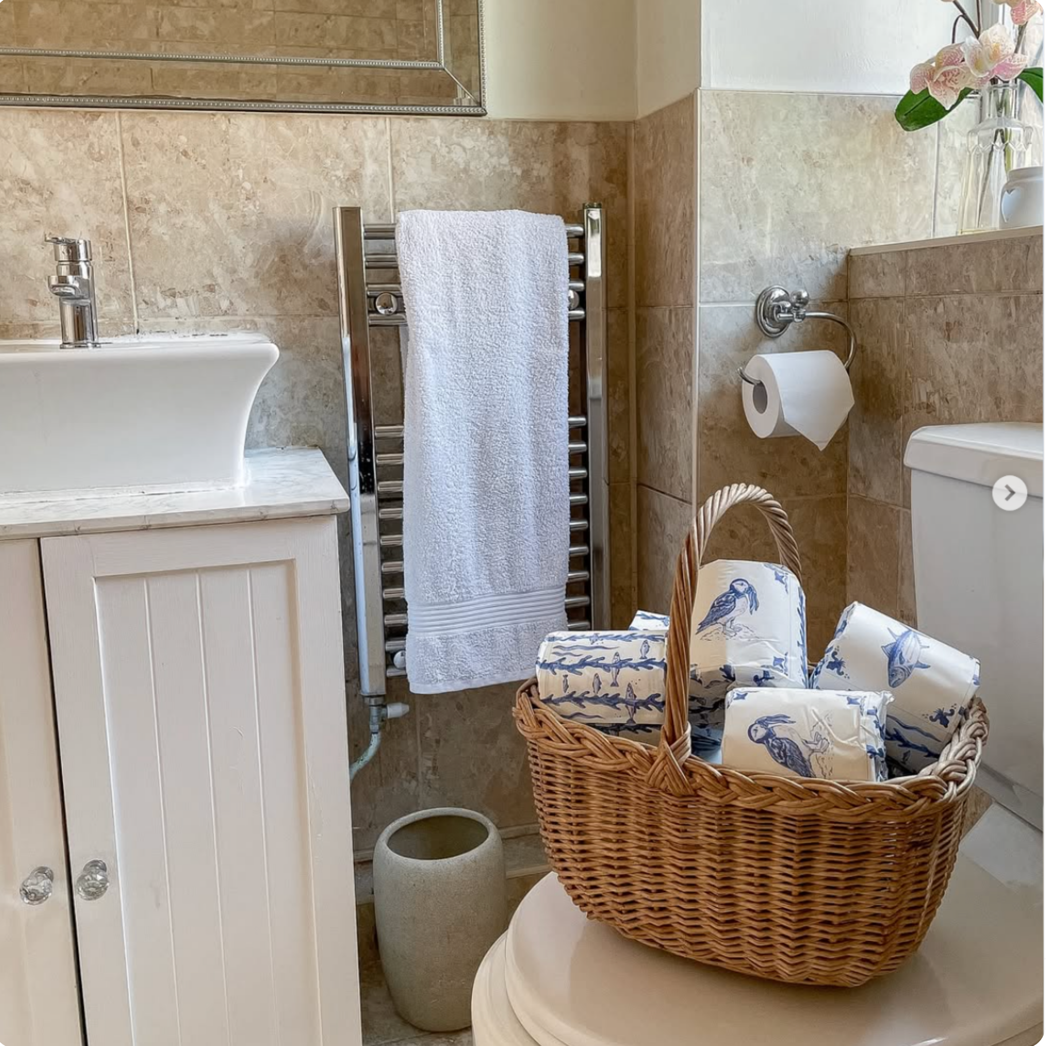 Bathroom with a basket of towels on a toilet, sink, and towel rack.