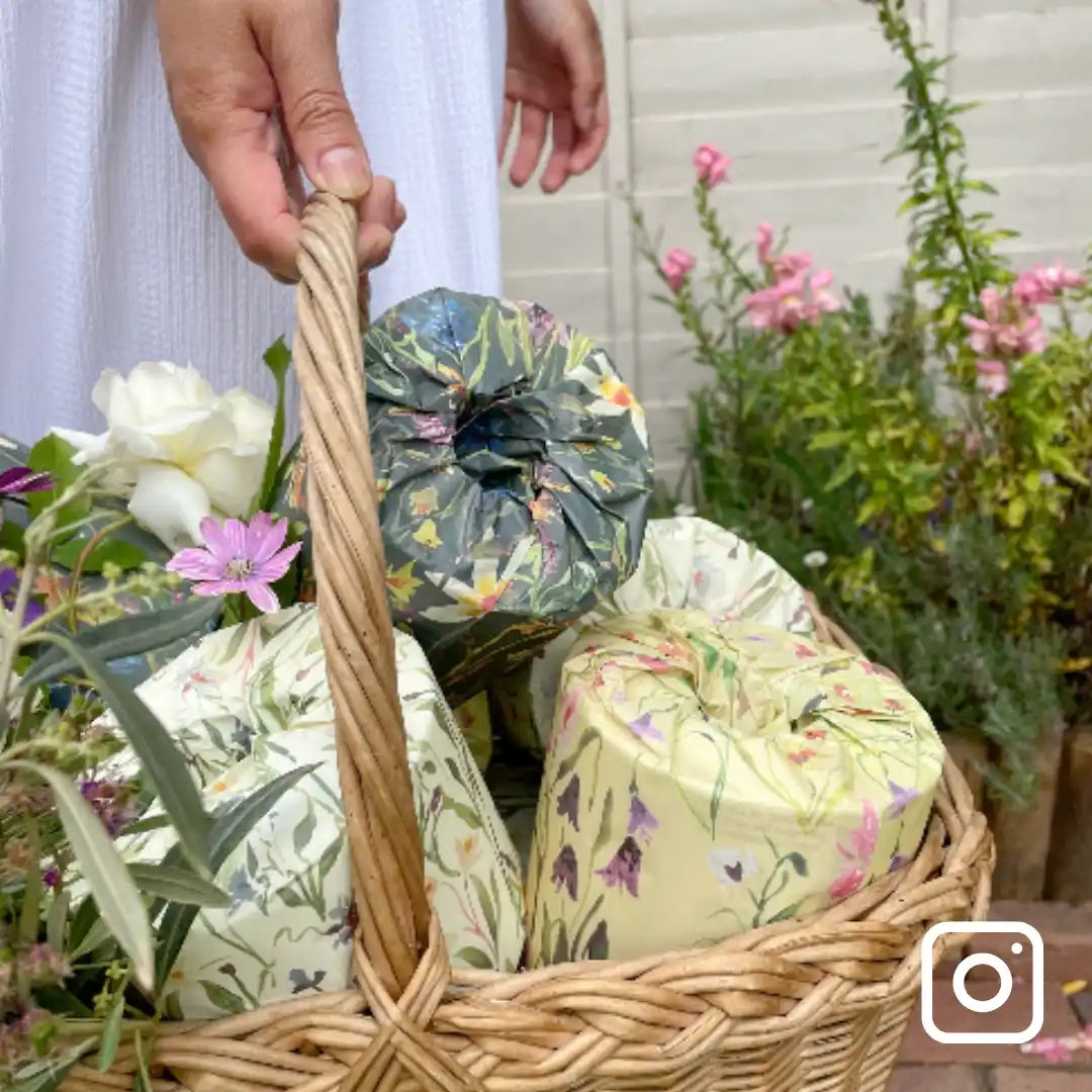 Wicker basket with floral-patterned toilet rolls against a garden background